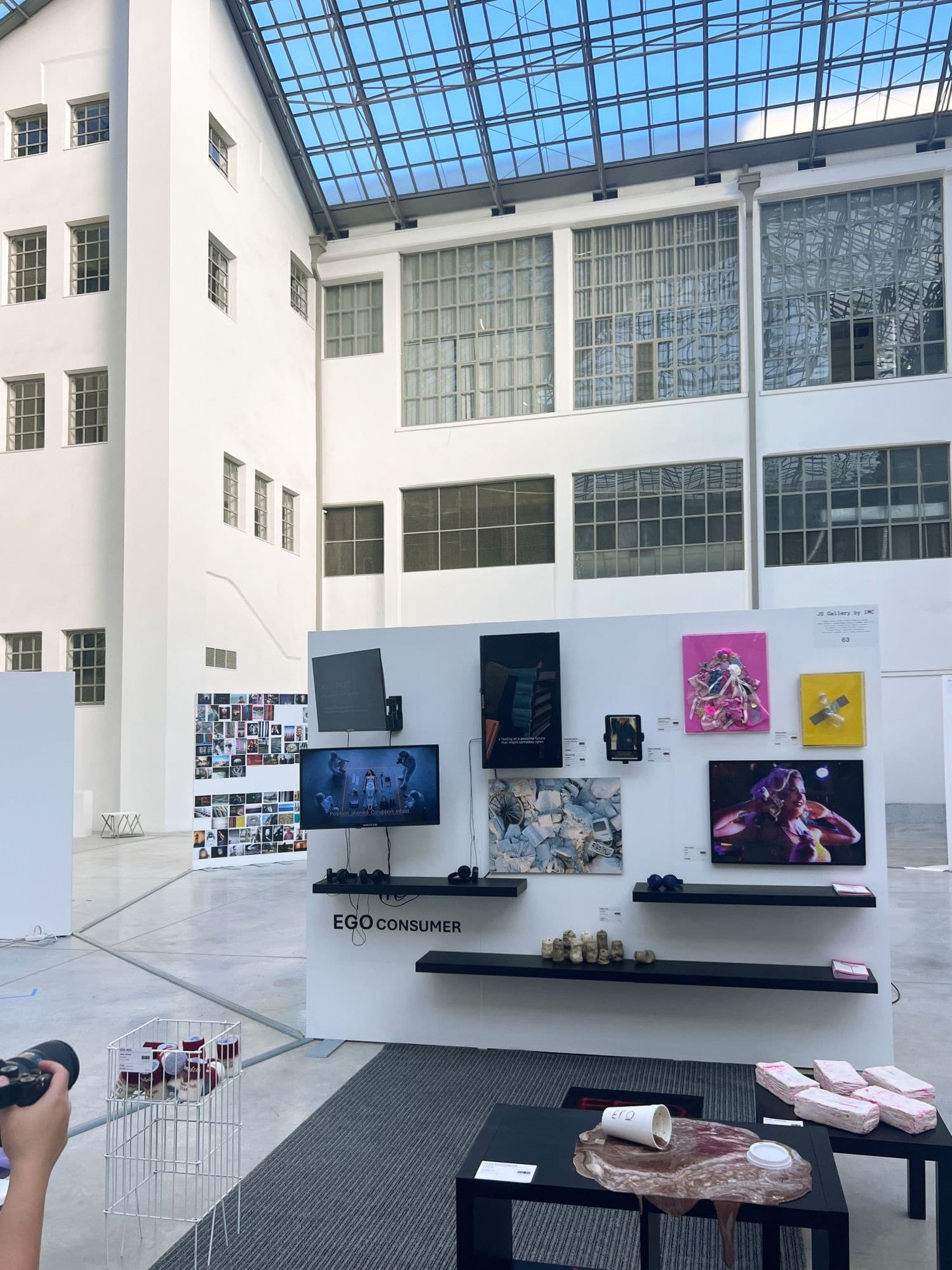 The EGO CONSUMER wall: screens, works and the bricks laid out on a low table