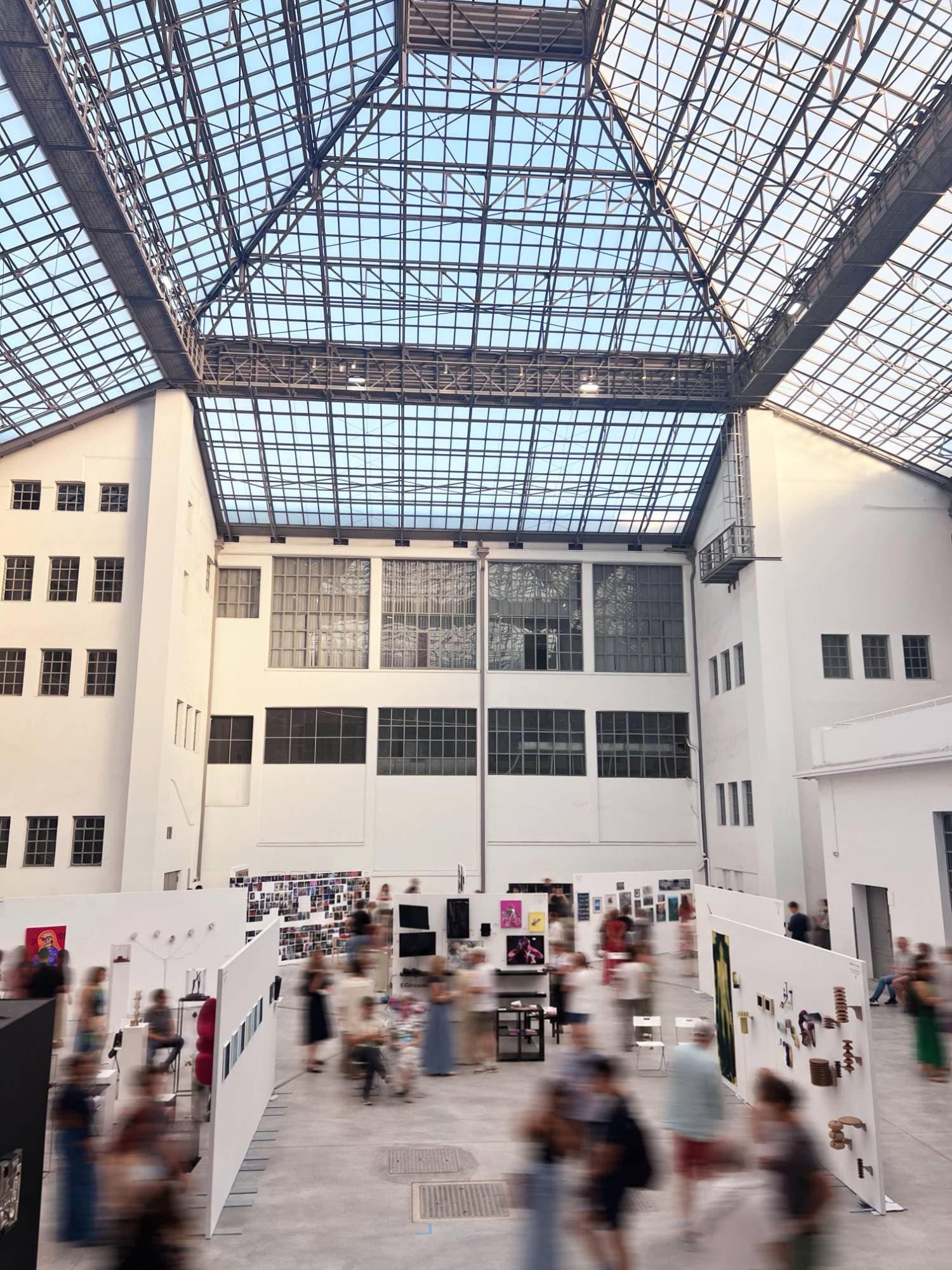 The glass-roofed hall of the Tobacco Factory, white partition walls and visitors moving between them