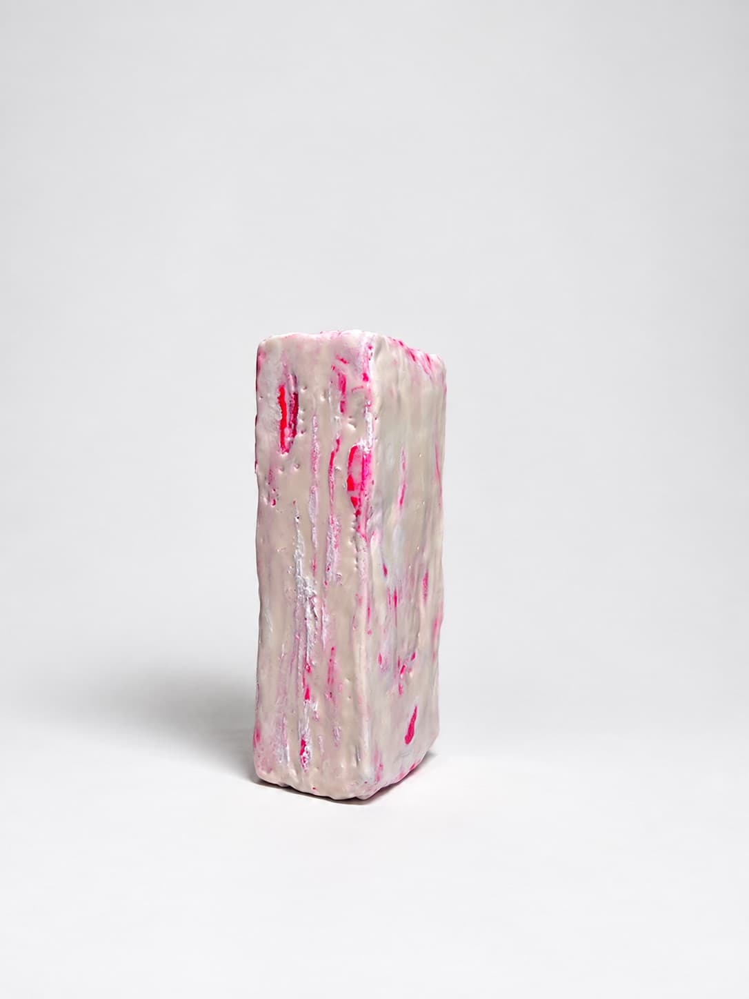 The same object standing on end, its waxed side streaked with pink