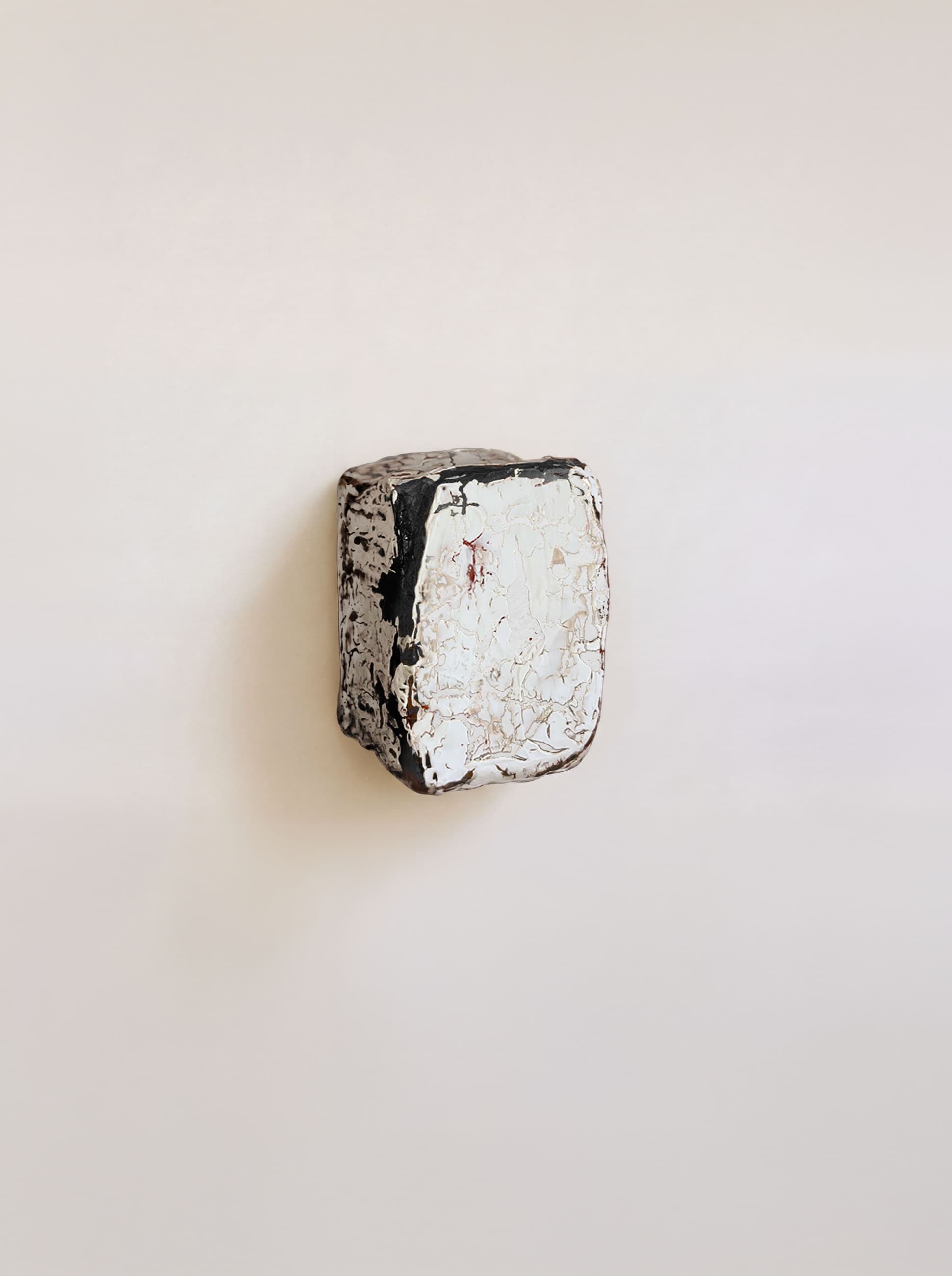 A brick of textile waste, one half black and one half white, mounted on a wall
