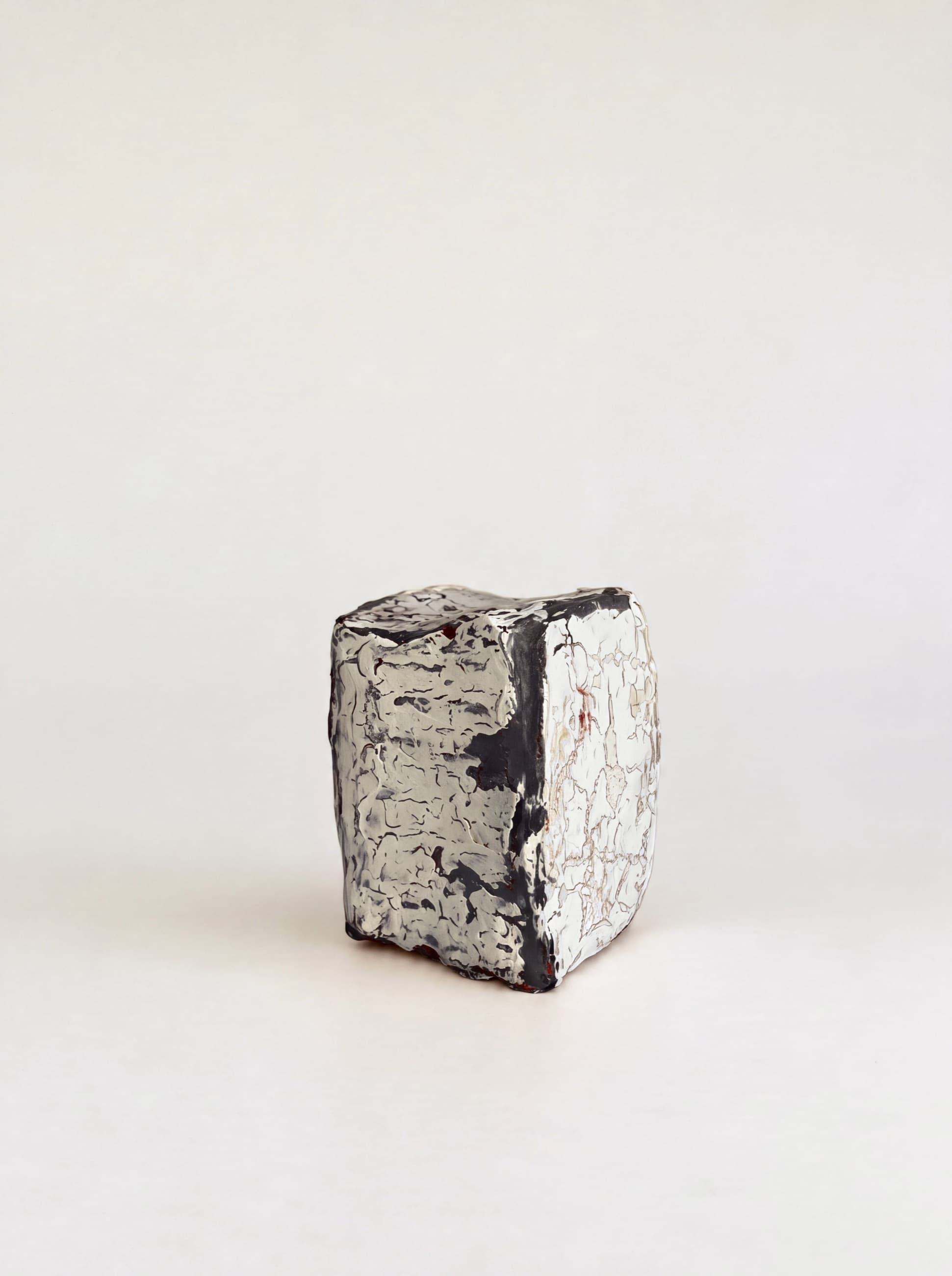 The same object standing on a pale ground, its black and white faces meeting at the corner