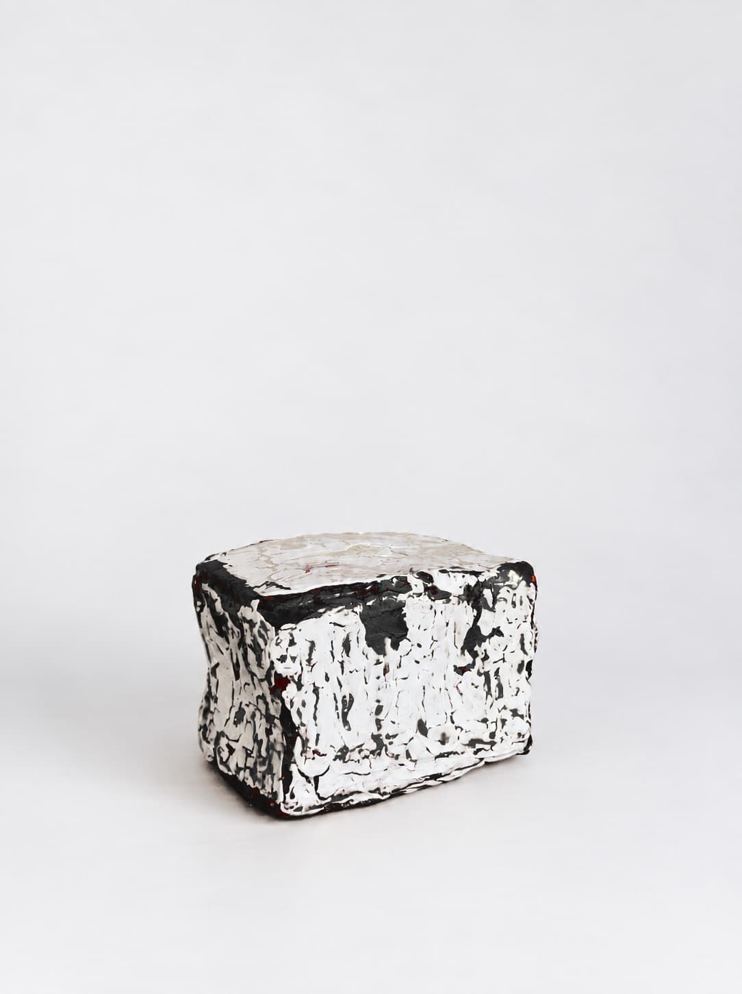 The object lying on its side, the white crackled surface breaking over the black beneath
