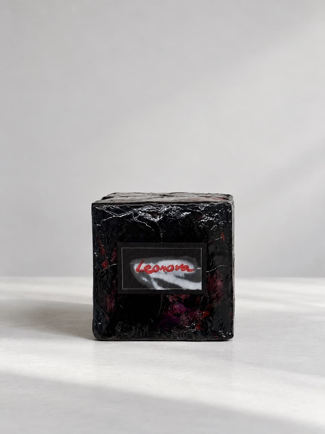 The same cube seen square on, a small label set into the black face and signed in red
