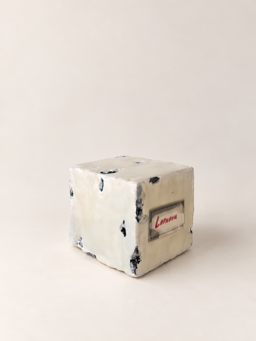 A small label set into the side of the cube, signed in red