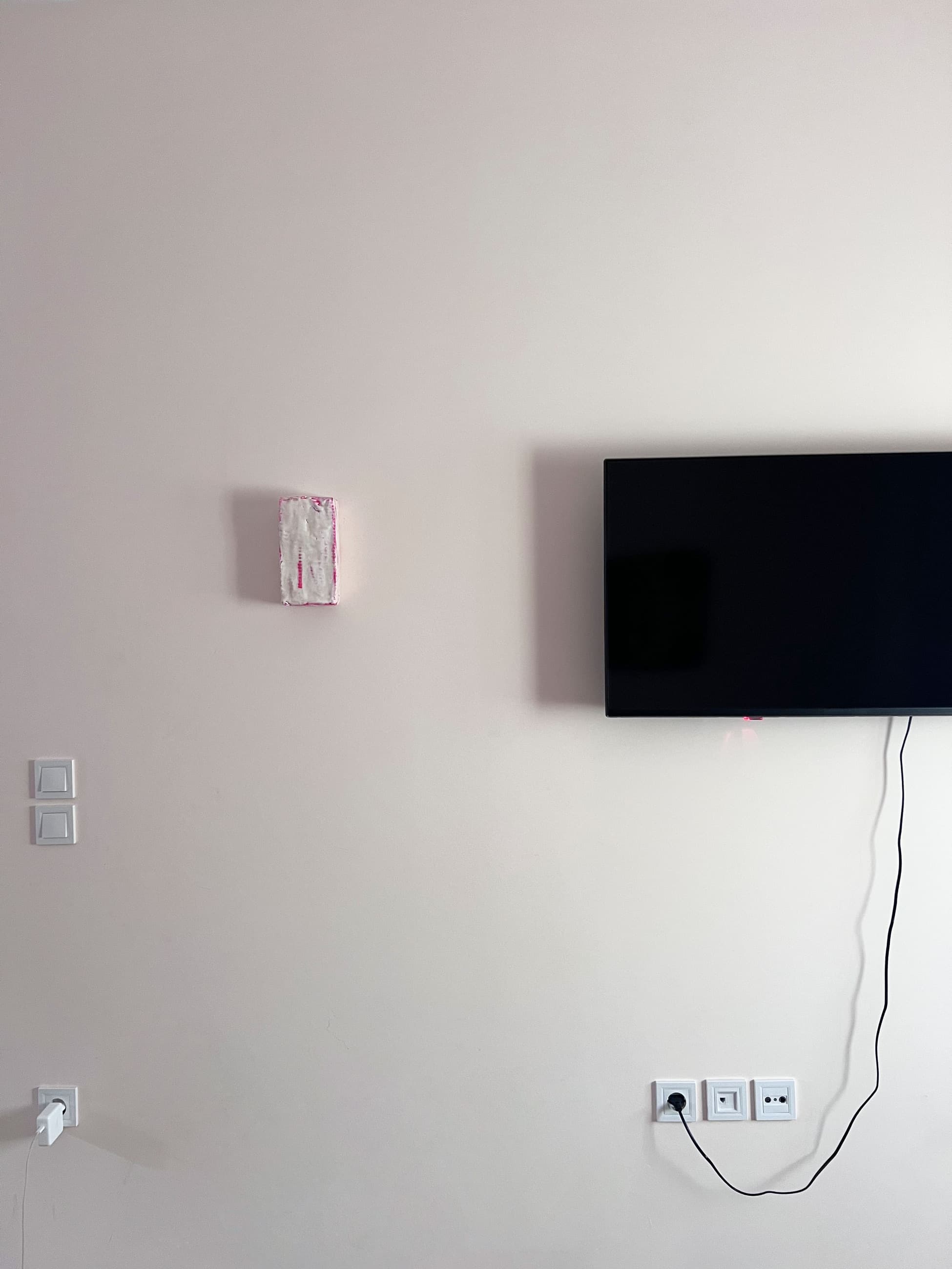 The object hung on a domestic wall beside a wall-mounted television and its cable