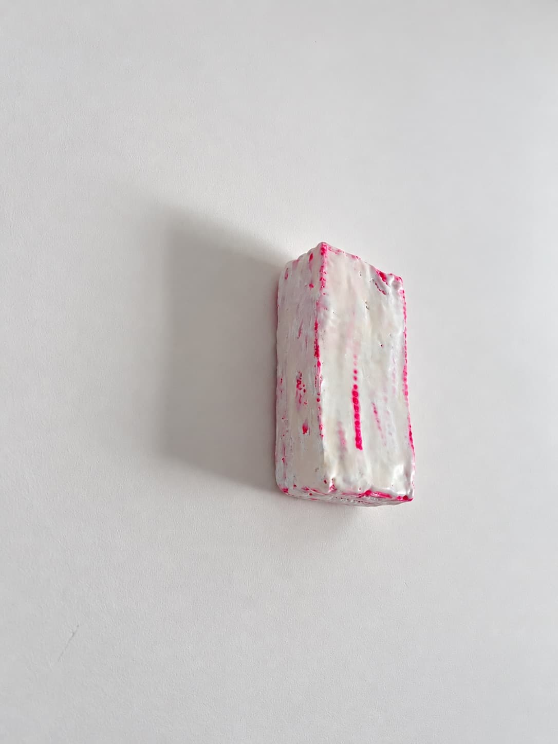 The object seen from below and to the side, throwing a soft shadow on the wall