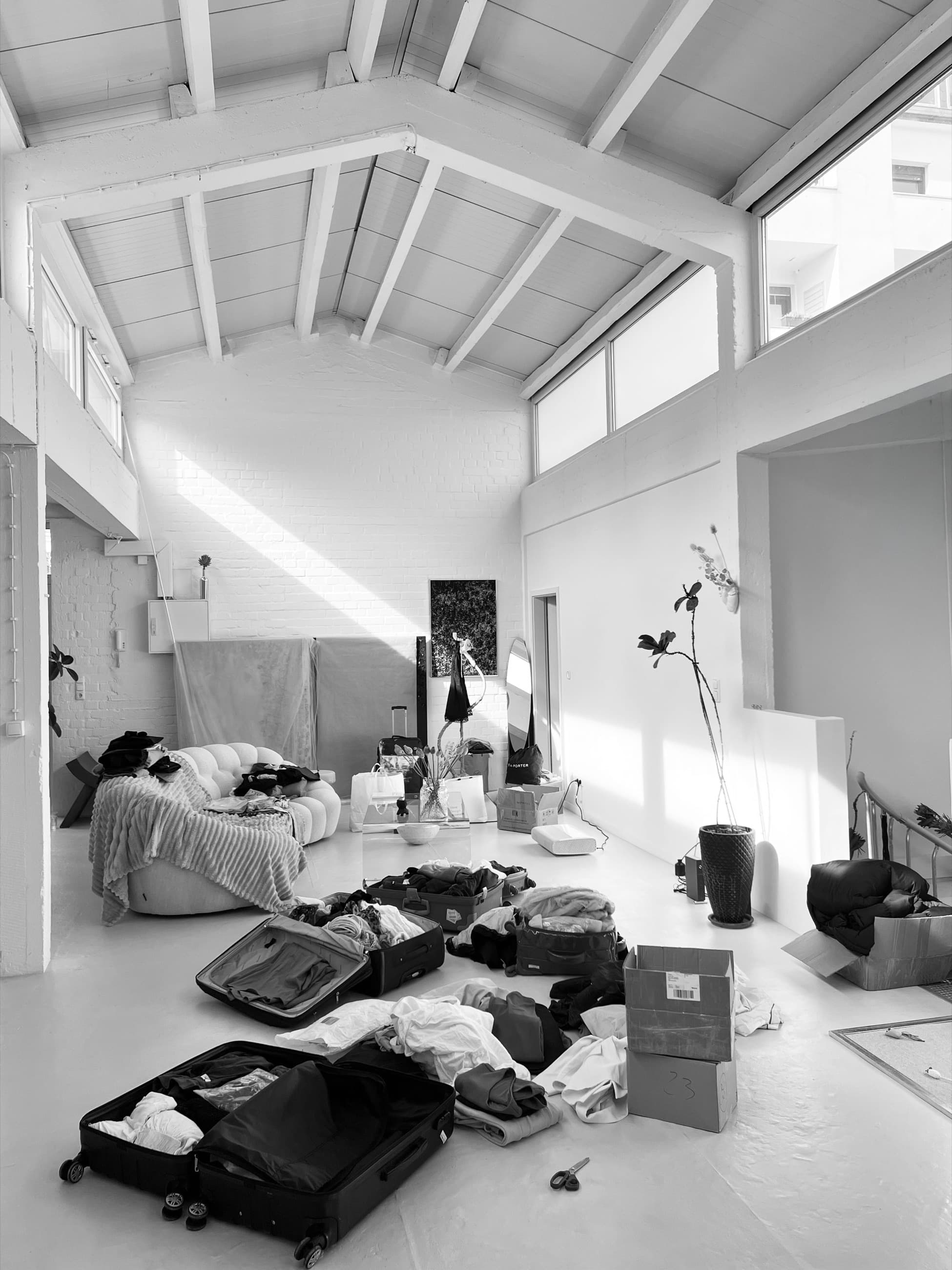 The studio under a pitched roof, open cases and heaped cloth across the floor