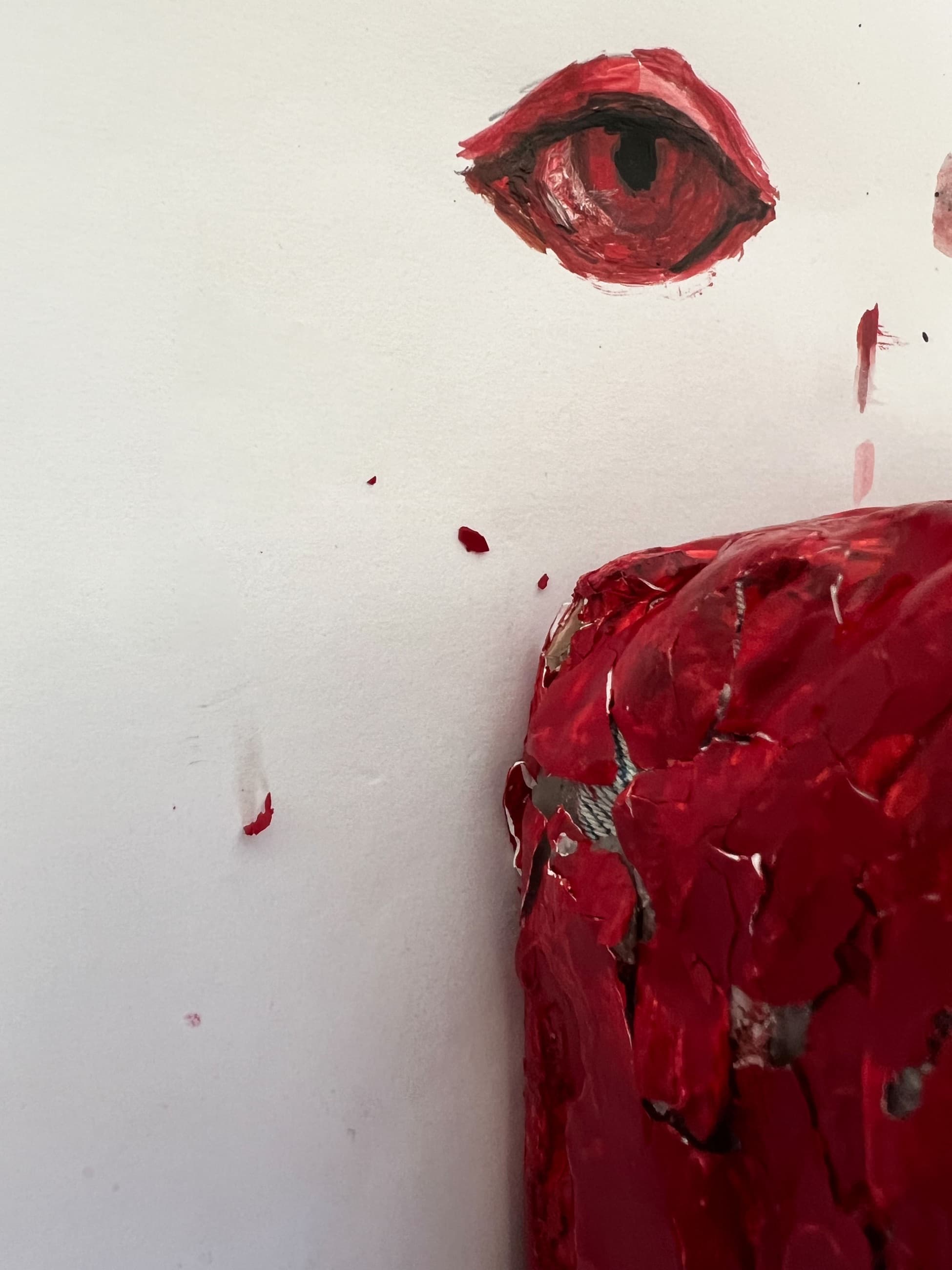 A red eye painted on a white wall above a red waxed brick