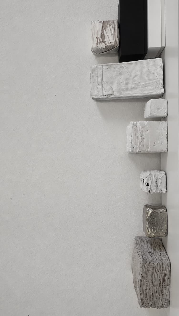 Pale bricks set into a white wall in a vertical line